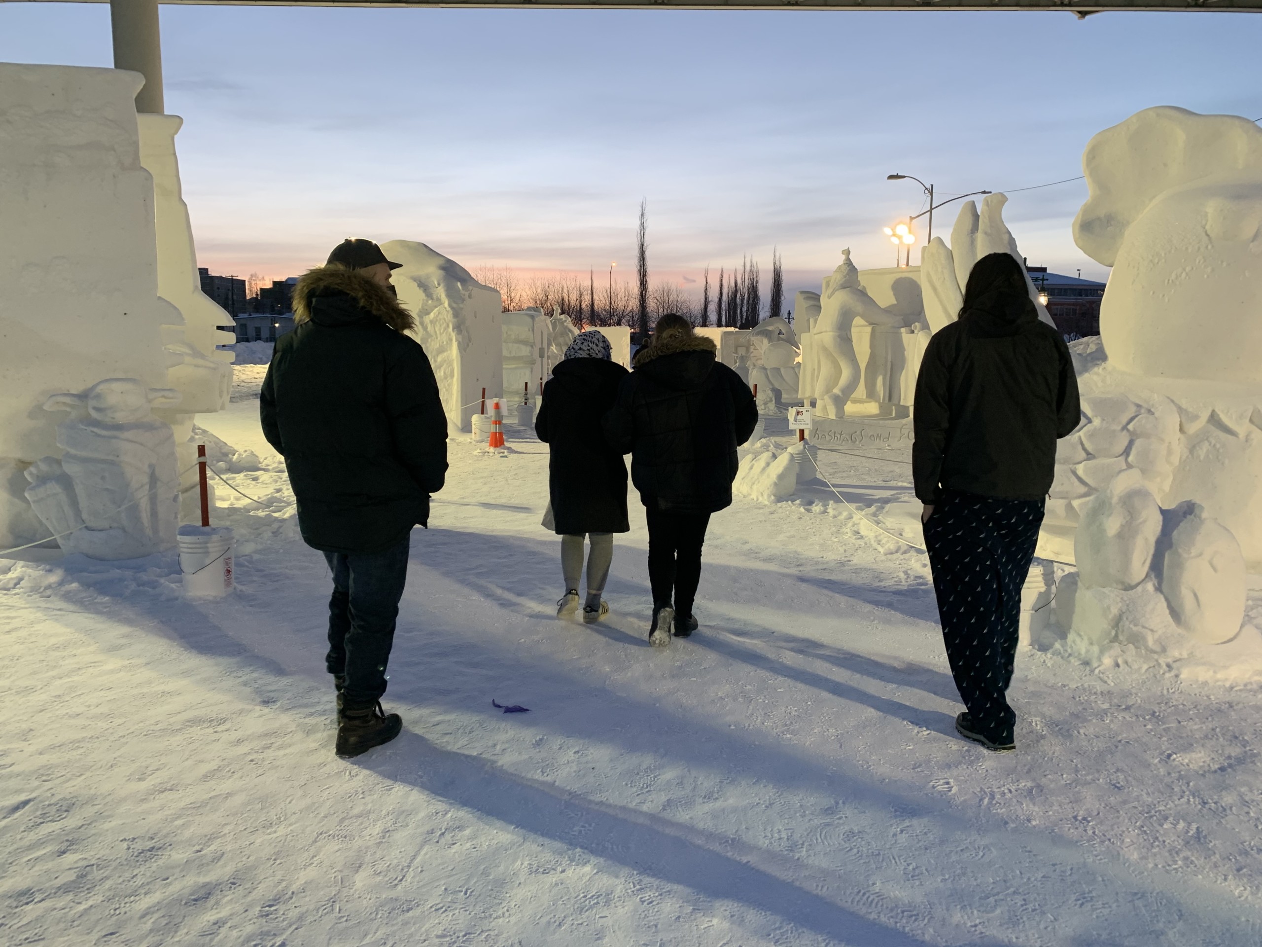 people walking by snow sculptures